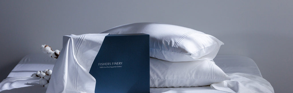 Fishers Finery Certified Egyptian Cotton Sheet Set on a bed with two pillows and gift box and piece of cotton behind the pillows