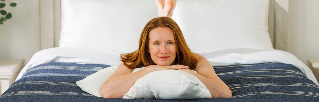 Woman on a bed with her legs crossed and arms folded on a white mulberry silk pillowcase