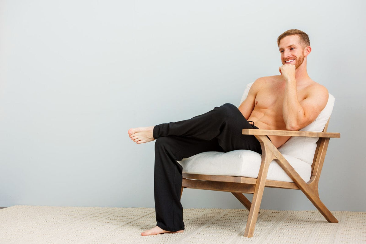 Man in black lounge pants relaxing in a wooden armchair