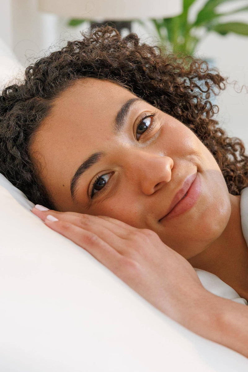 Natural white silk pillowcase with smooth, lustrous texture on woman resting head.