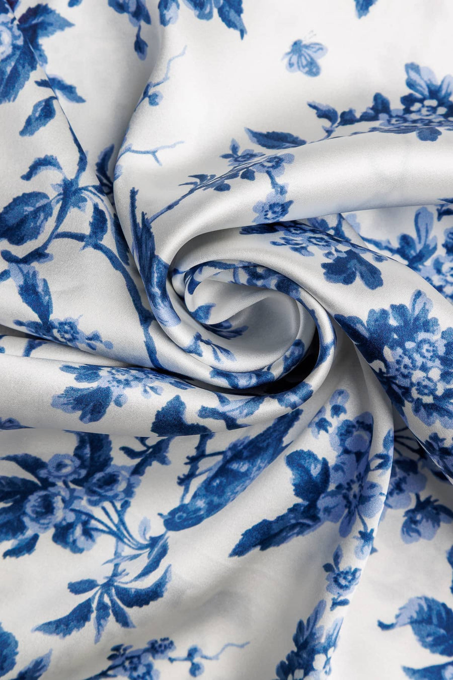 Natural white silk fabric with intricate blue floral print, smooth and lustrous texture.