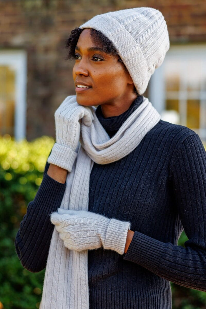 Cream silk knit beanie, scarf, and fingerless gloves set on model wearing black sweater.