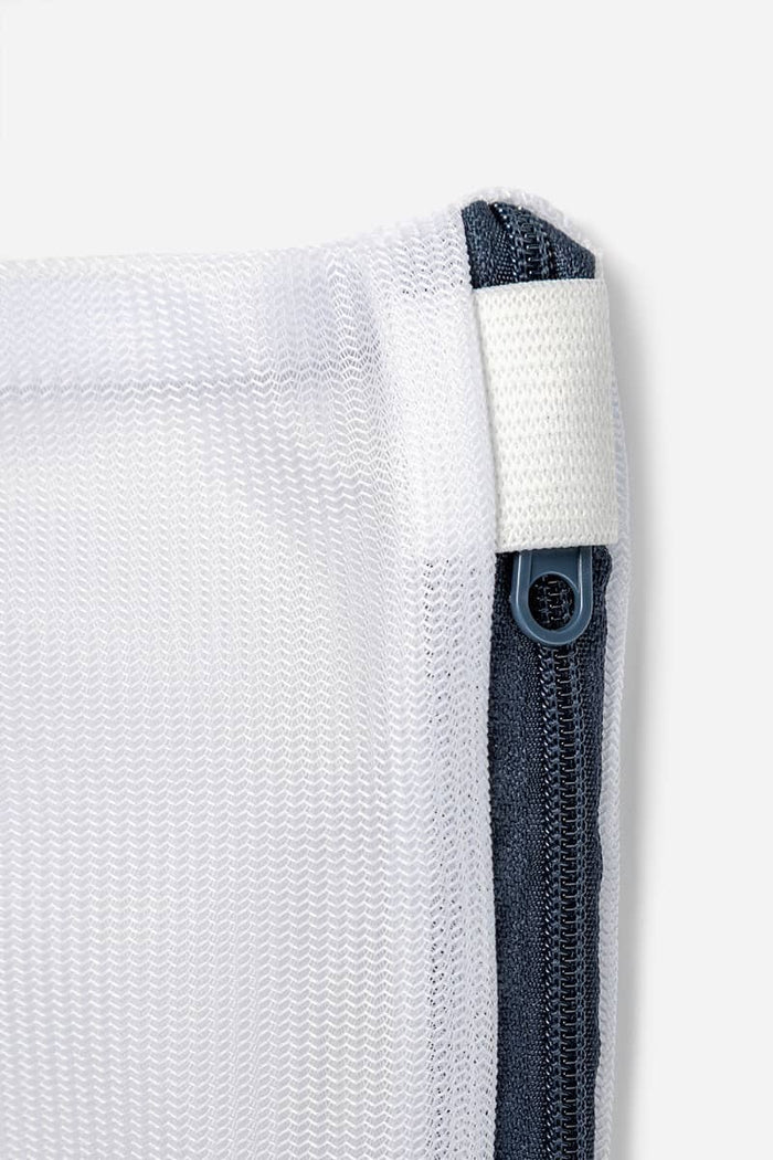 White silk pillowcase corner with hidden zipper closure and navy lining detail.