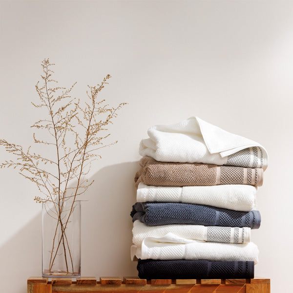 Fishers Finery organic cotton rice weave towels stacked in neutral colors on a wooden bench