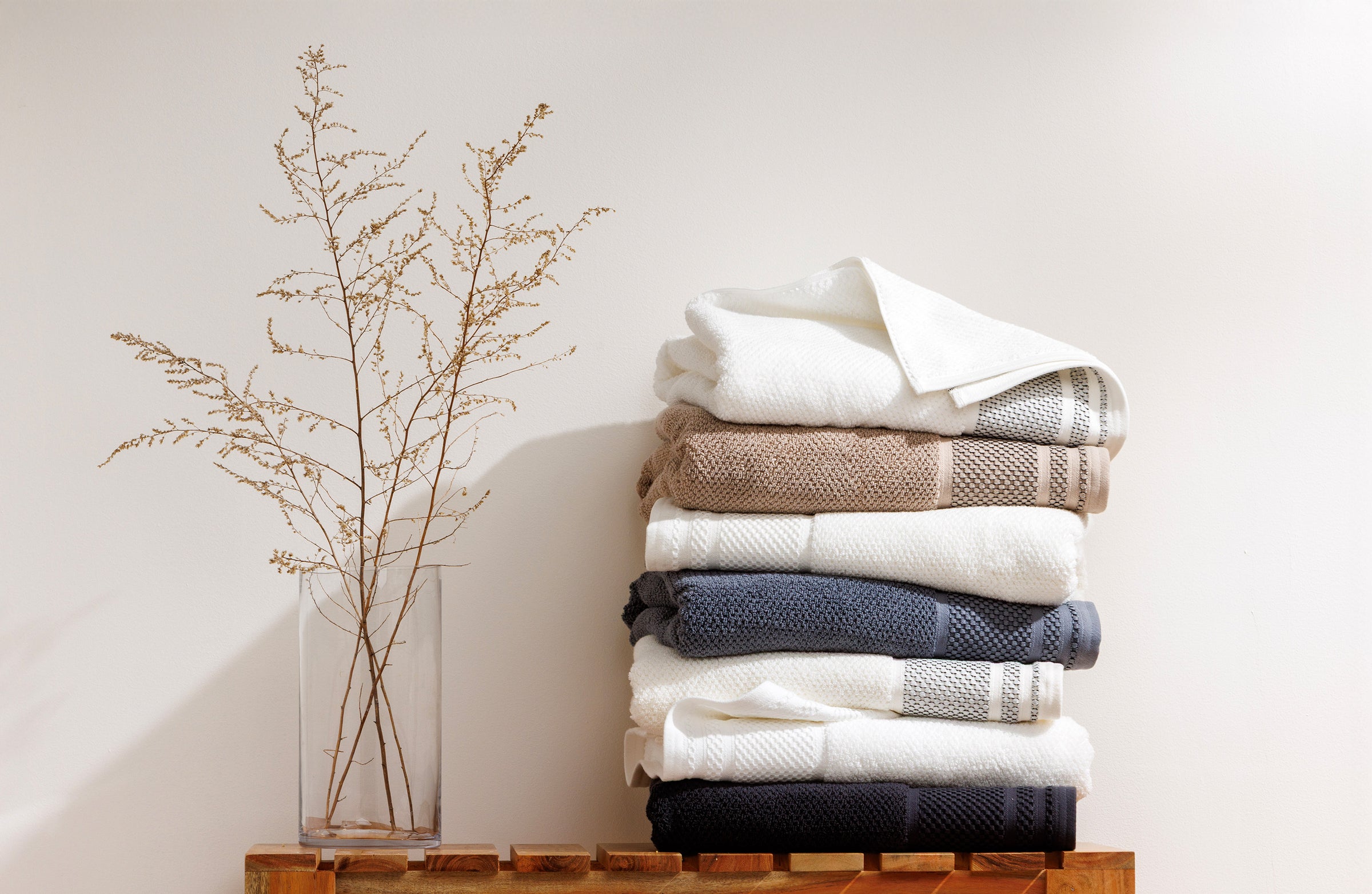 Fishers Finery organic cotton rice weave towels stacked in neutral colors on a wooden bench
