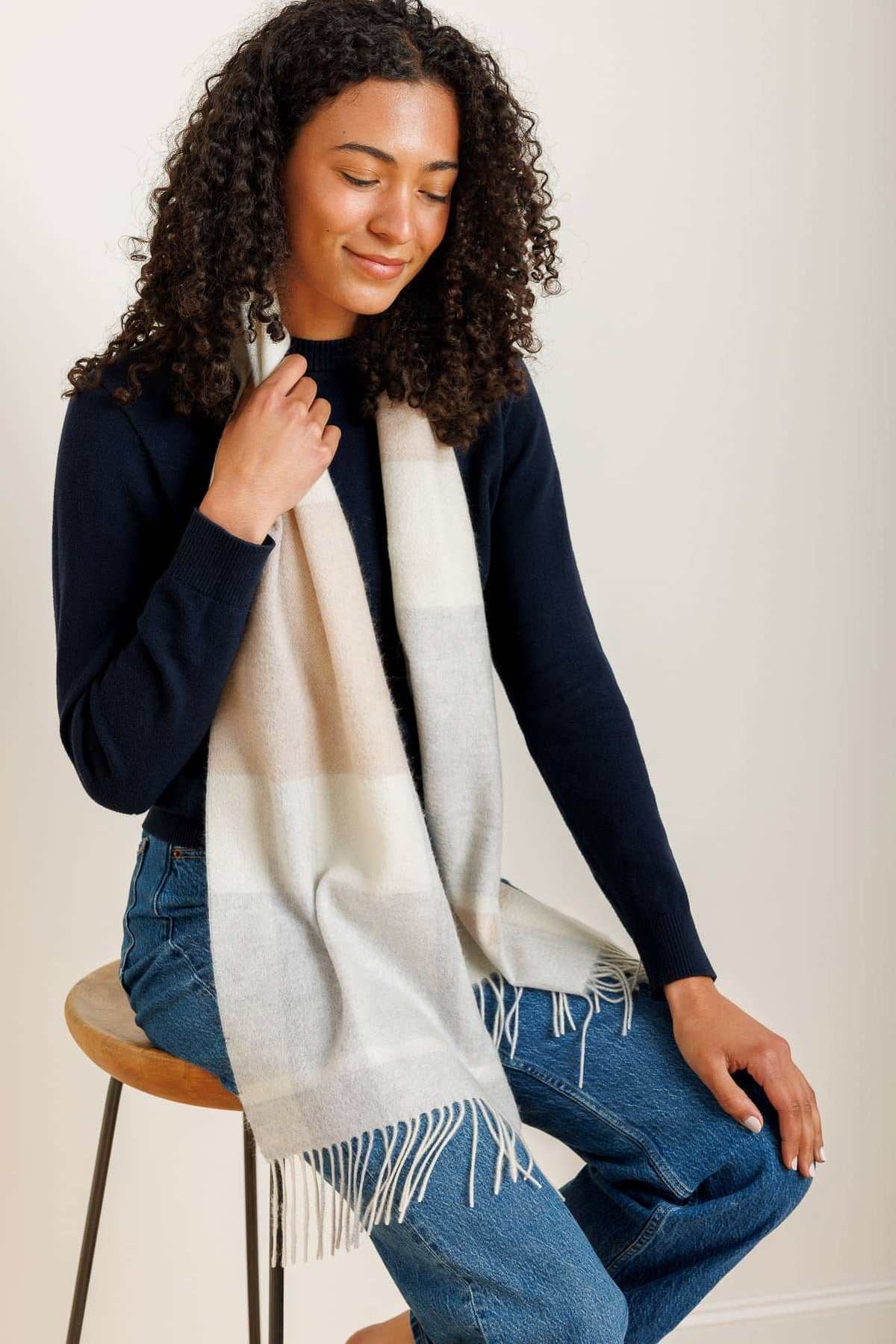 Silk scarf with cream, gray, and tan plaid pattern and fringed edges wrapped around neck.