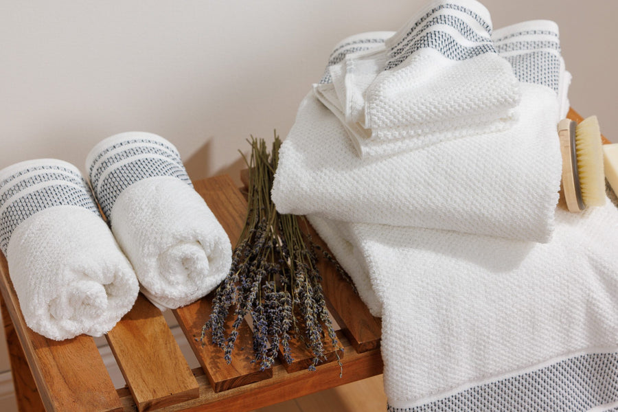 Rolled organic cotton hand towels with dried lavender on a wooden bench