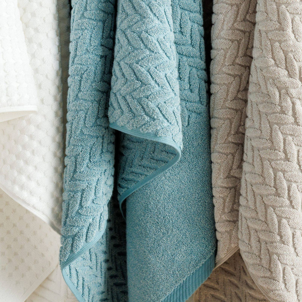 Textured organic cotton towels in blue and taupe hanging side by side