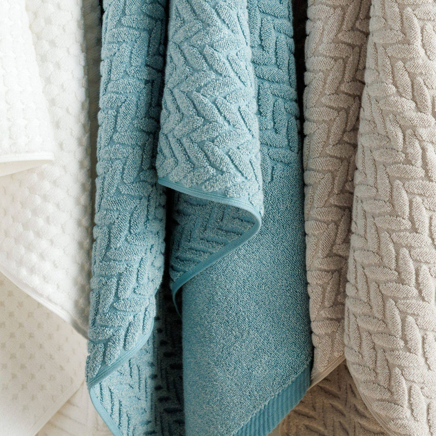 Textured organic cotton towels in blue and taupe hanging side by side
