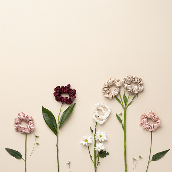 Scrunchies on stems with leaves and flowers against a beige background