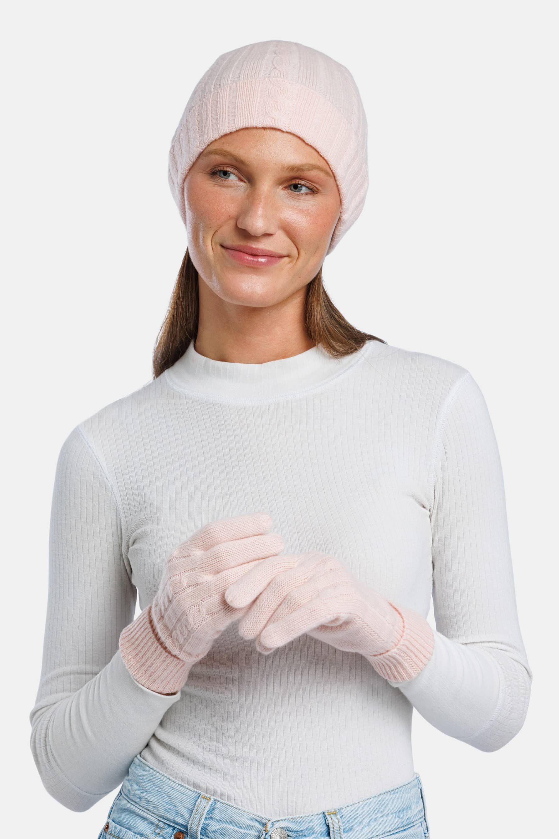 Pink cashmere knit beanie and matching gloves on model with white top.