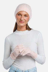 Pink cashmere knit beanie and matching gloves on model with white top.