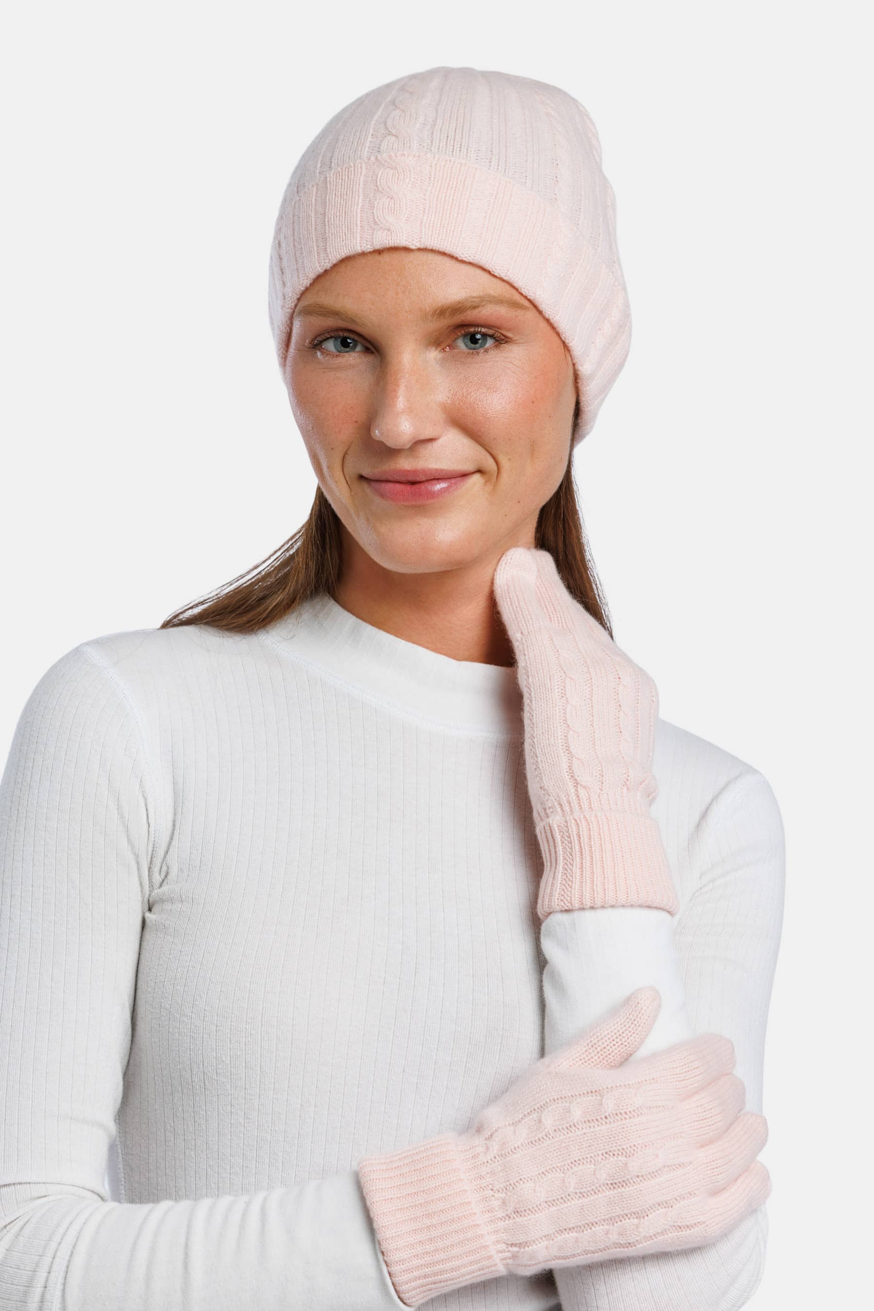 Pink cashmere knit beanie and matching gloves on model with white top.