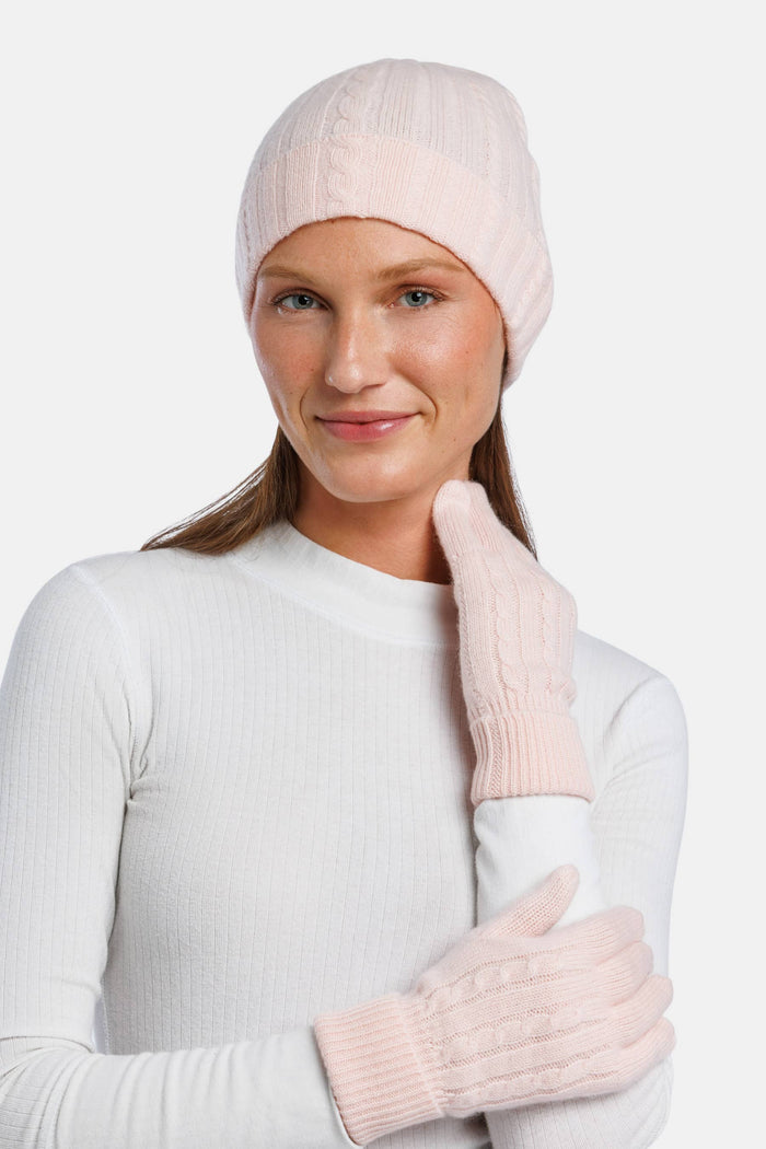 Pink cashmere knit beanie and matching gloves on model with white top.