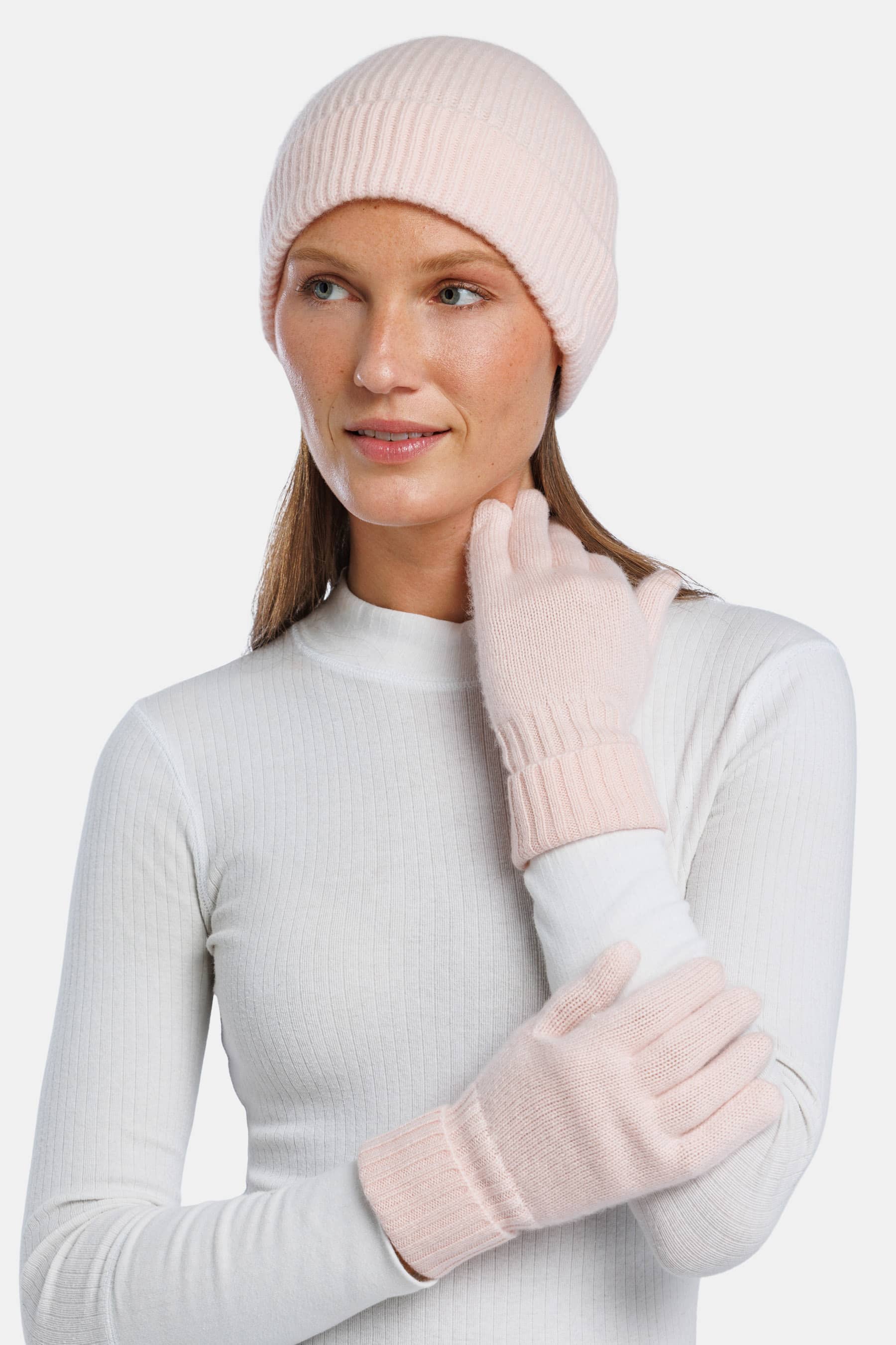 Pink cashmere knit beanie and matching gloves on model with white top.