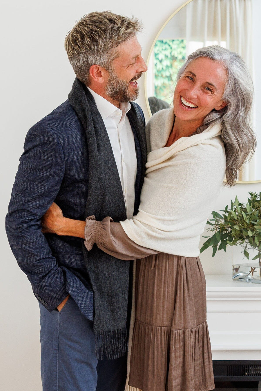 Cream cashmere shawl draped over a woman's shoulders with fringe detailing.