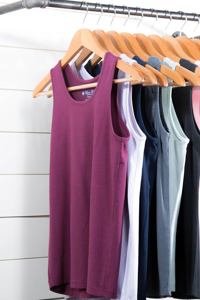 Silk sleeveless tank tops in purple, white, blue, gray, and black hanging on wooden hangers.