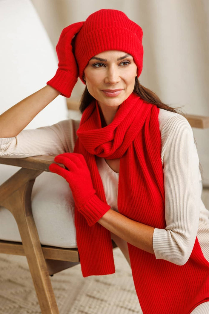 Cardinal red silk scarf with matching knit gloves and beanie on woman wearing beige top.
