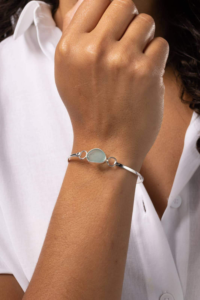 Delicate silk wrap bracelet with a round aqua stone and silver accents on wrist.