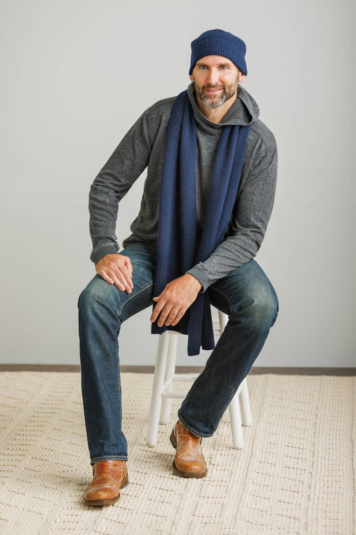 Navy silk scarf paired with gray knit hat and casual outfit on seated man.